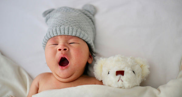 Neugeborenes gähnt und trägt einen Hut. Unsplash-Kredit Minnie Zhou.